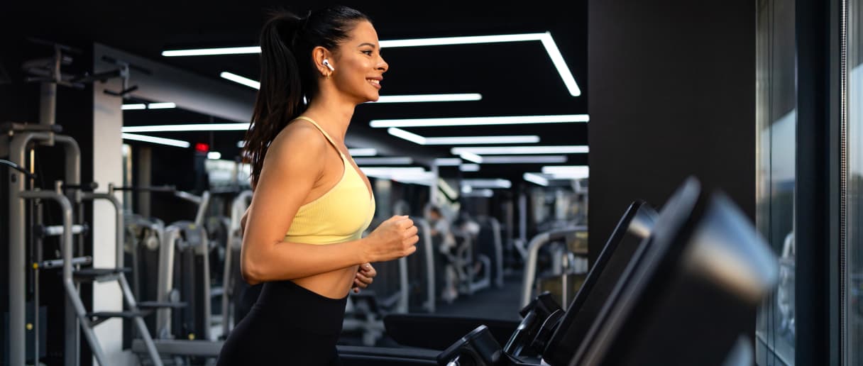 Gost vežba na traci za trčanje u modernom hotelskom fitnes centru sa kardio i spravama za trening snage.