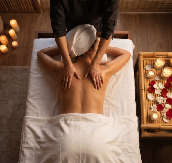 Terapeut izvodi klasičnu masažu leđa u mirnom hotelskom spa i wellness okruženju uz sveće.